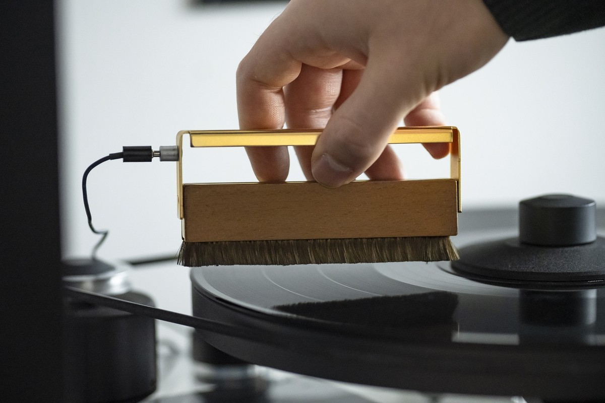 Mano che passa una spazzola dorata su un disco