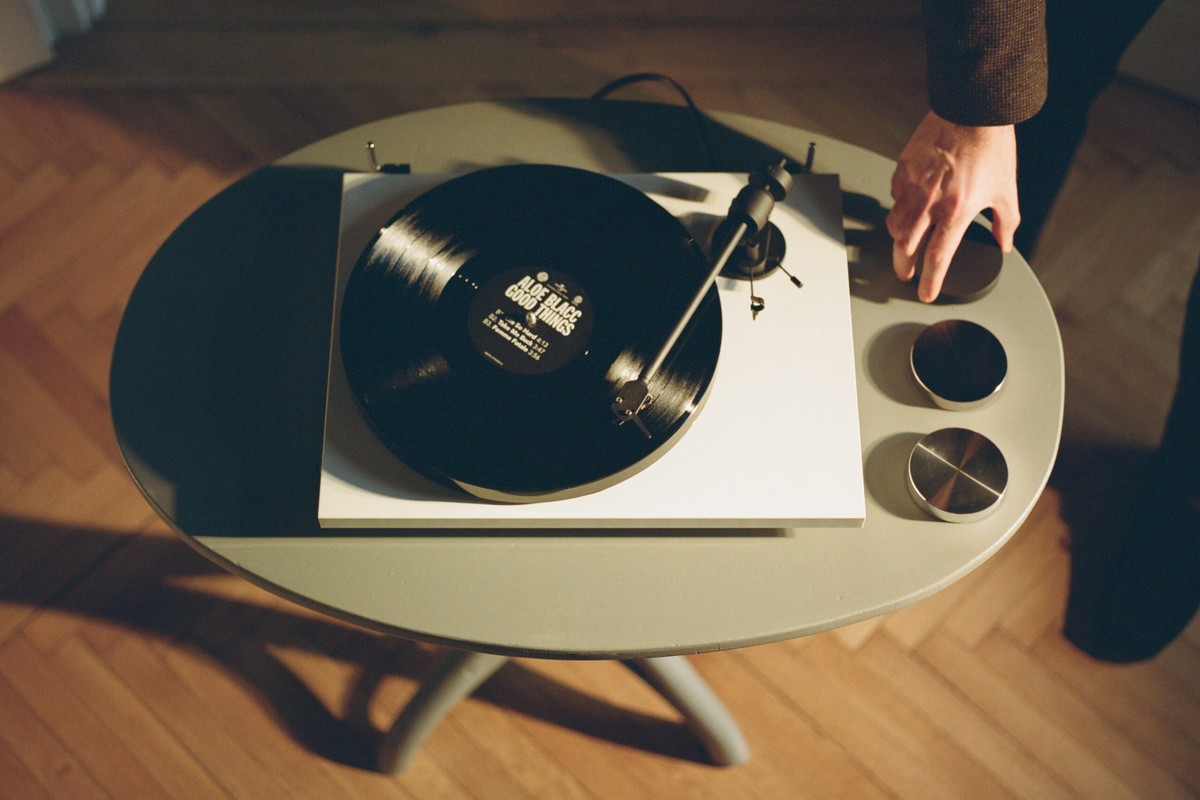 Hand placing a record on a white turntable