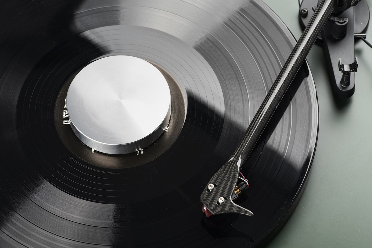 Polished silver puck on a record with the tonearm playing