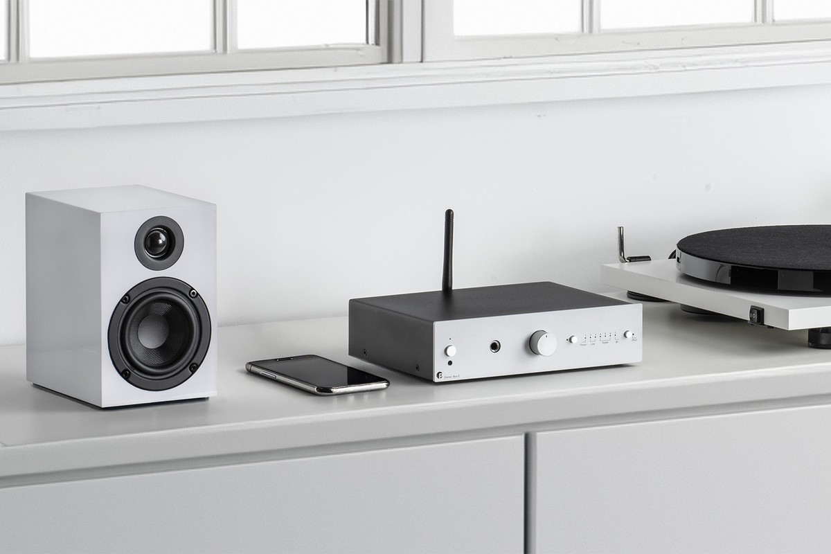 Amplificateur argent sur un buffet à côté d'une enceinte et d'une platine