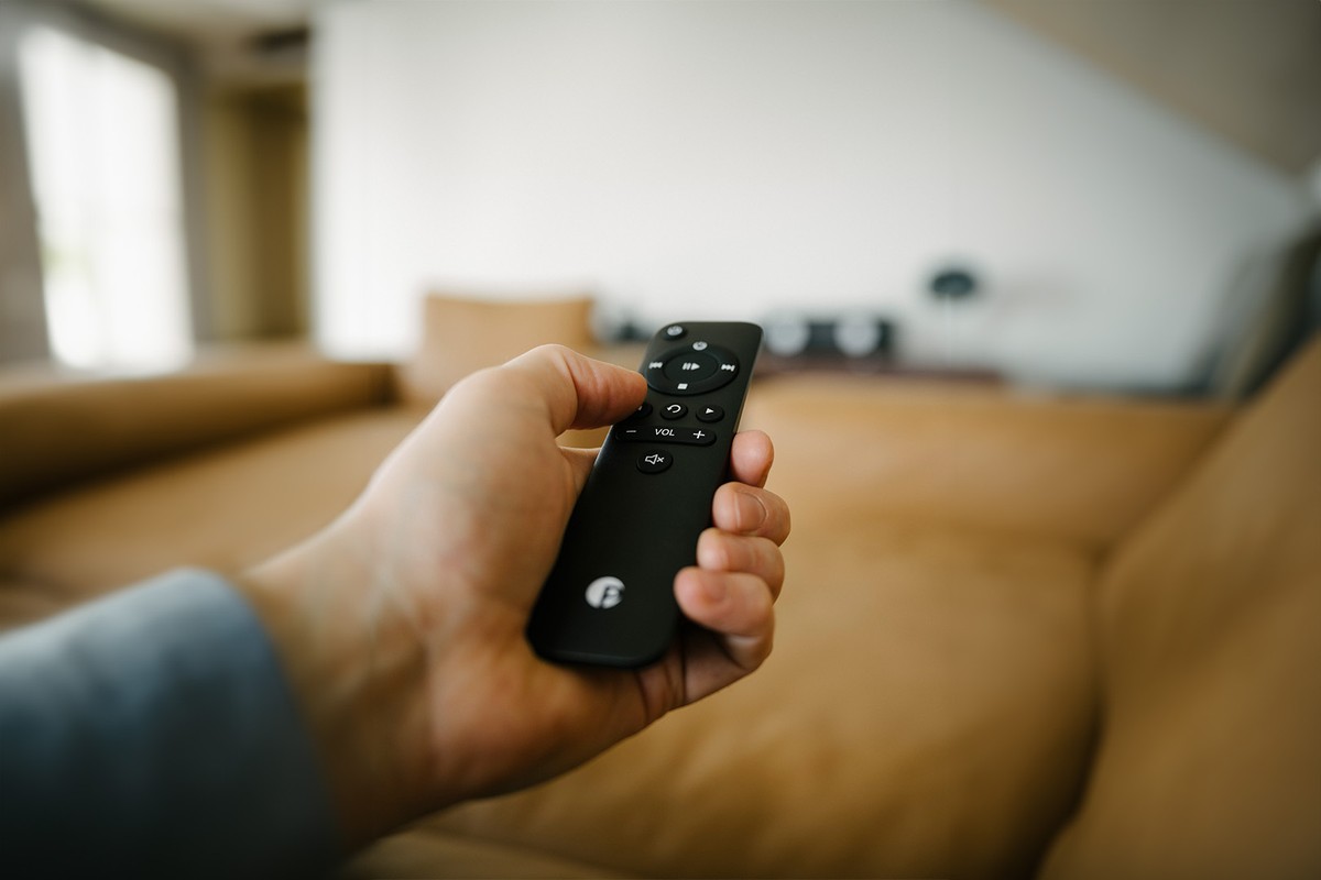 Main tenant la télécommande dans un salon