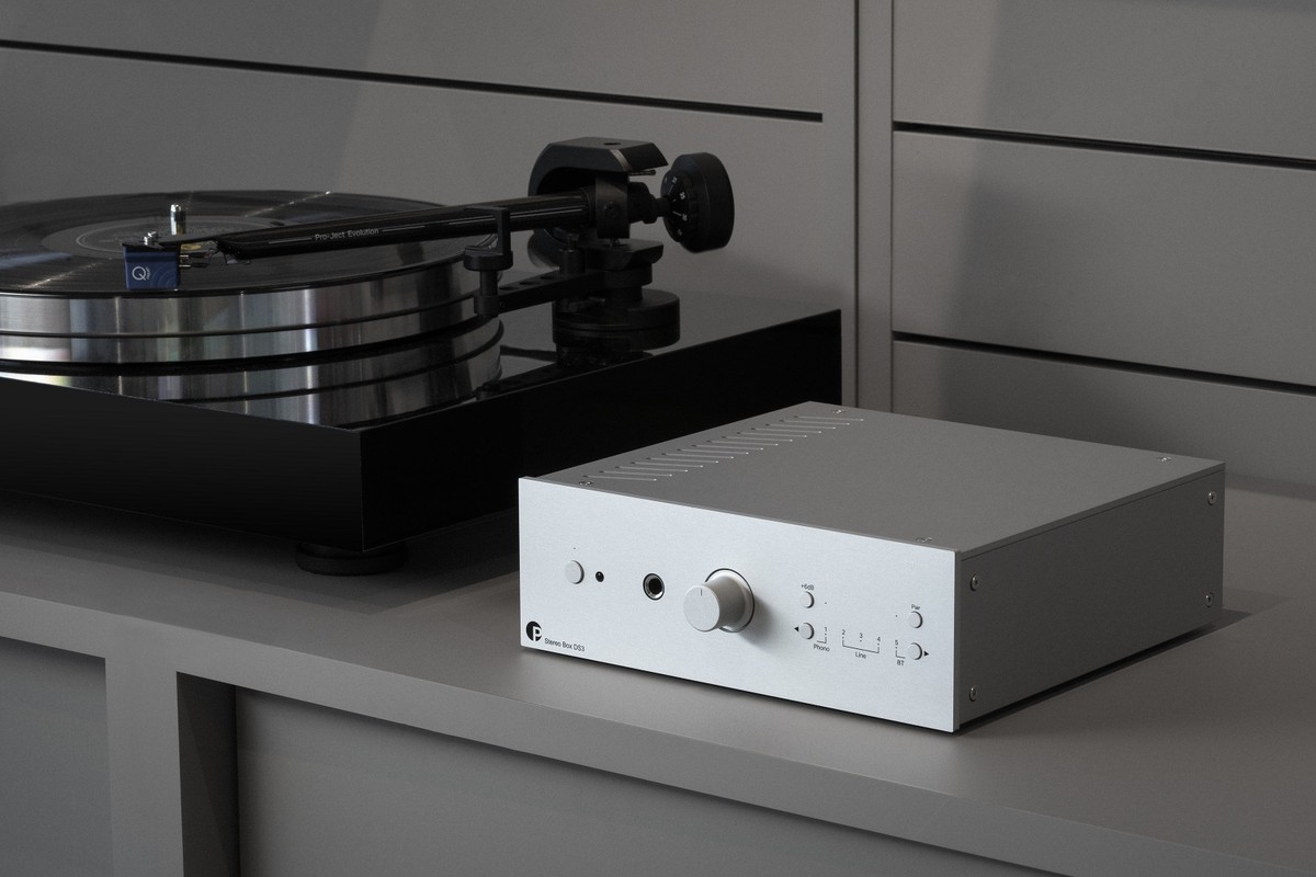 Amplificateur argent posé à côté d'une platine vinyle
