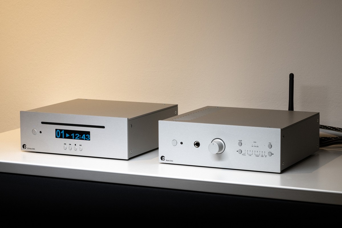 Amplificateur argent à côté d'un lecteur CD sur un meuble clair