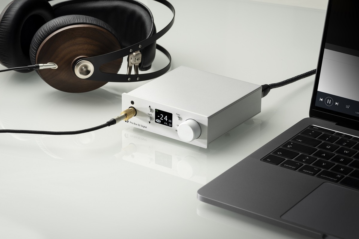 Préampli argent relié à un casque, à côté d'un ordinateur portable