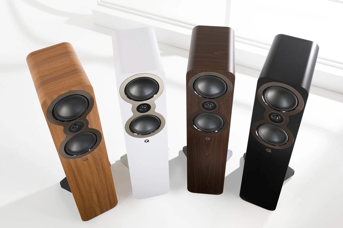 Four floorstanding speakers in light oak, white, dark walnut and black seen from above next to a window