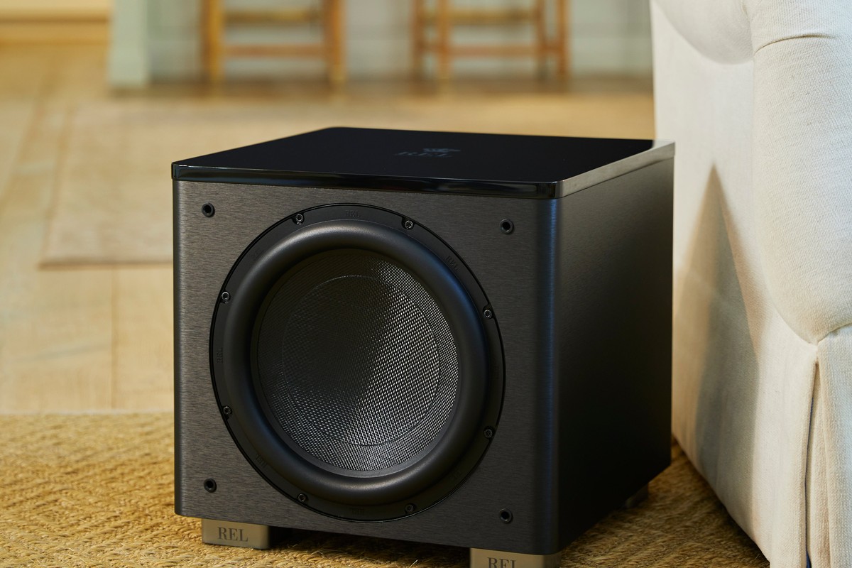Caisson de basses noir posé sur un tapis à côté d'un canapé