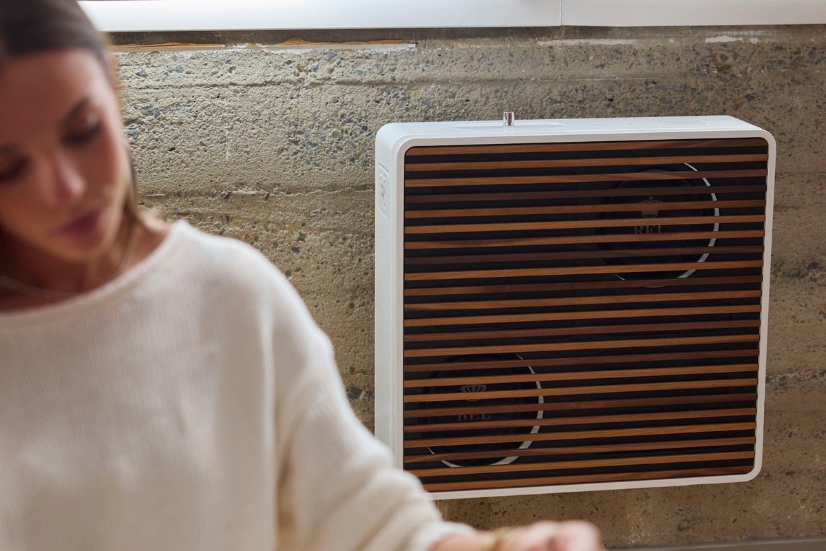 Weisser Subwoofer mit Holzabdeckung an der Wohnzimmerwand, eine Leserin im Vordergrund