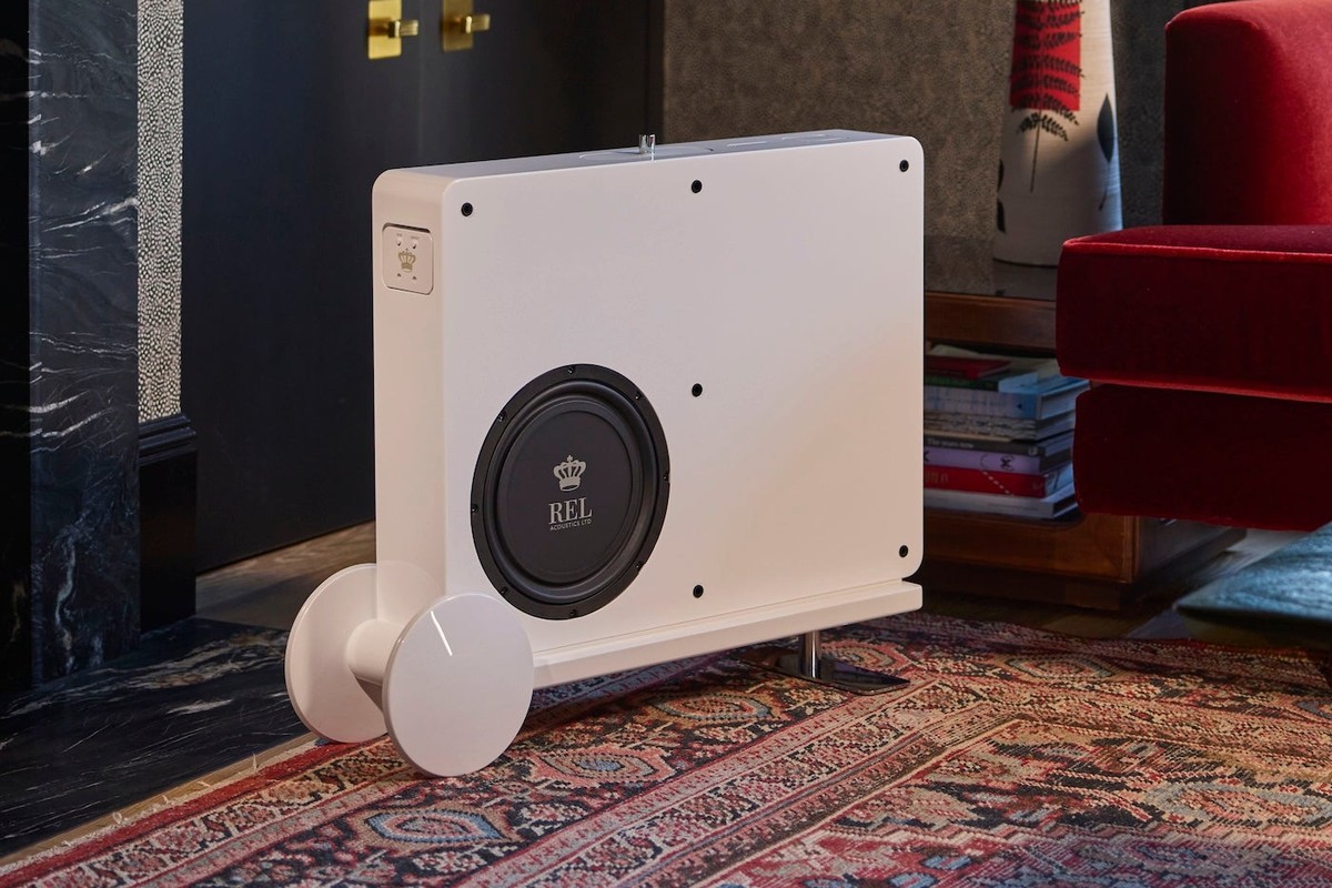White subwoofer without grille standing on its cart in a living room