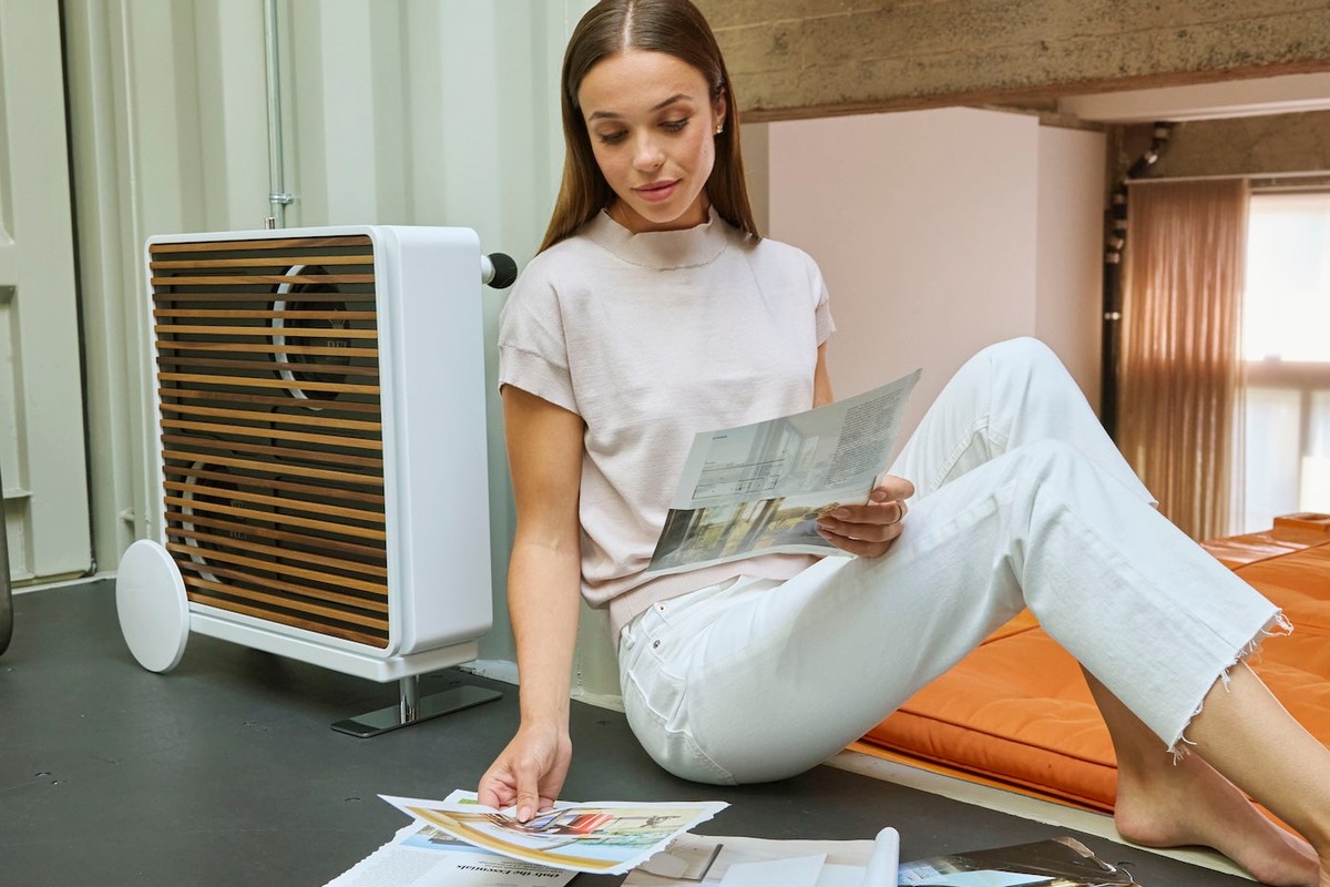 Subwoofer bianco con doghe in legno in un loft, accanto a una donna che legge