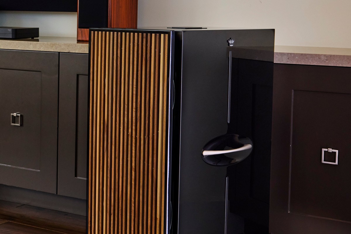 Schwarz glänzender Säulen-Subwoofer mit senkrechten Lamellen im Wohnzimmer