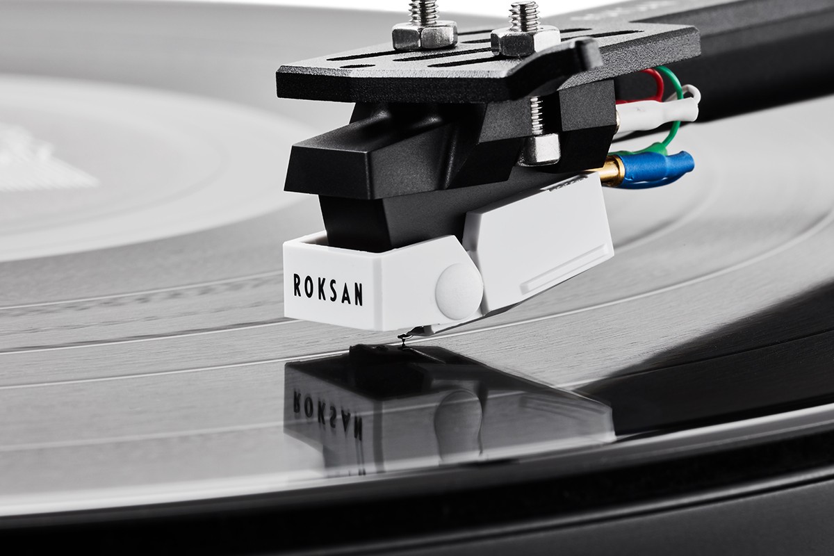 Phono cartridge resting in the groove of a black vinyl record