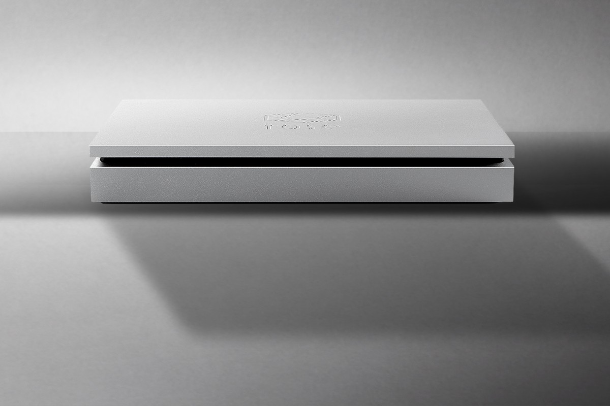 Boîtier argenté extra-plat posé sur une surface grise, ombre portée