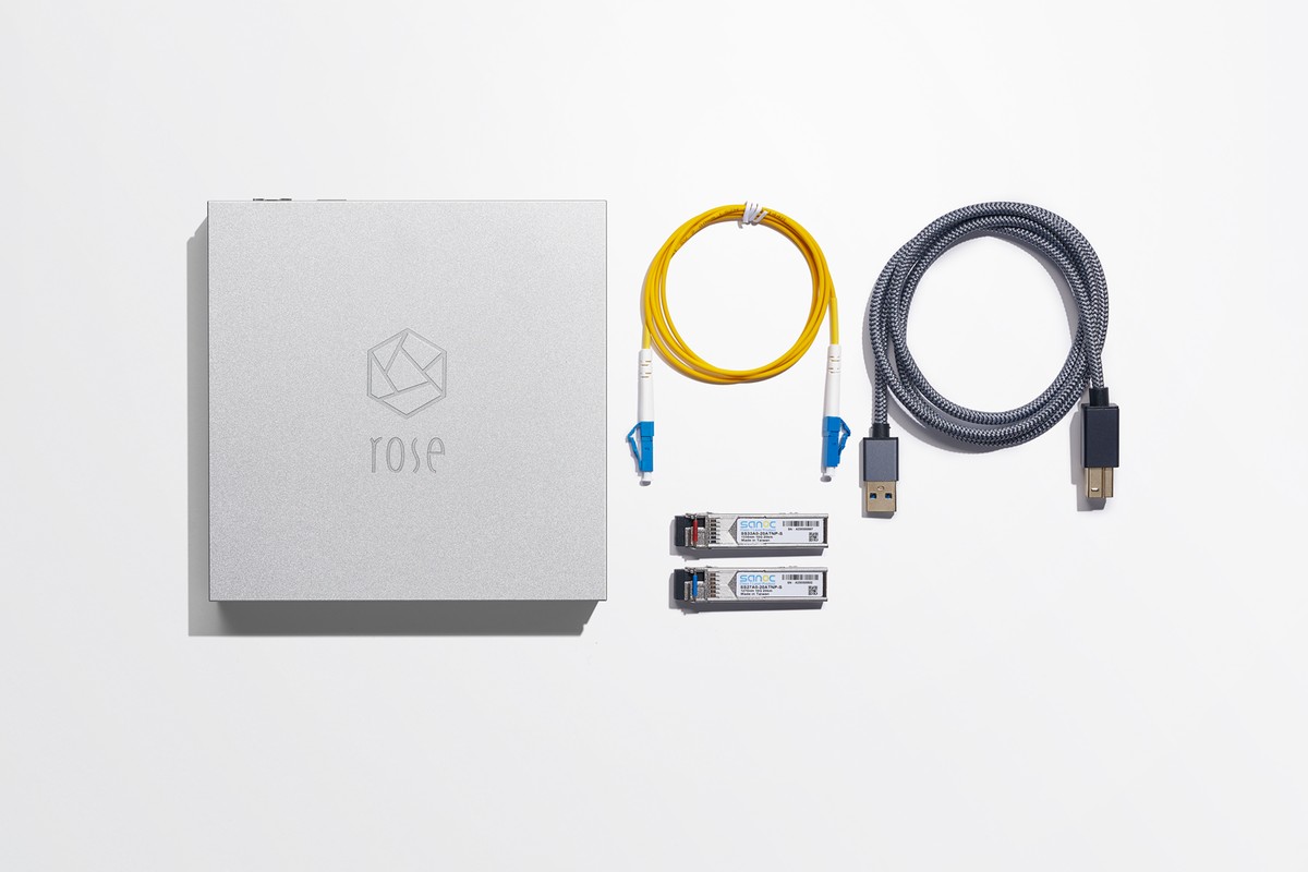 Hub argenté vu de dessus avec deux modules SFP, un câble optique jaune et un câble USB tressé