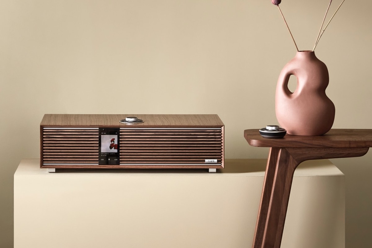Walnut speaker on a cream plinth, pink vase and walnut side table