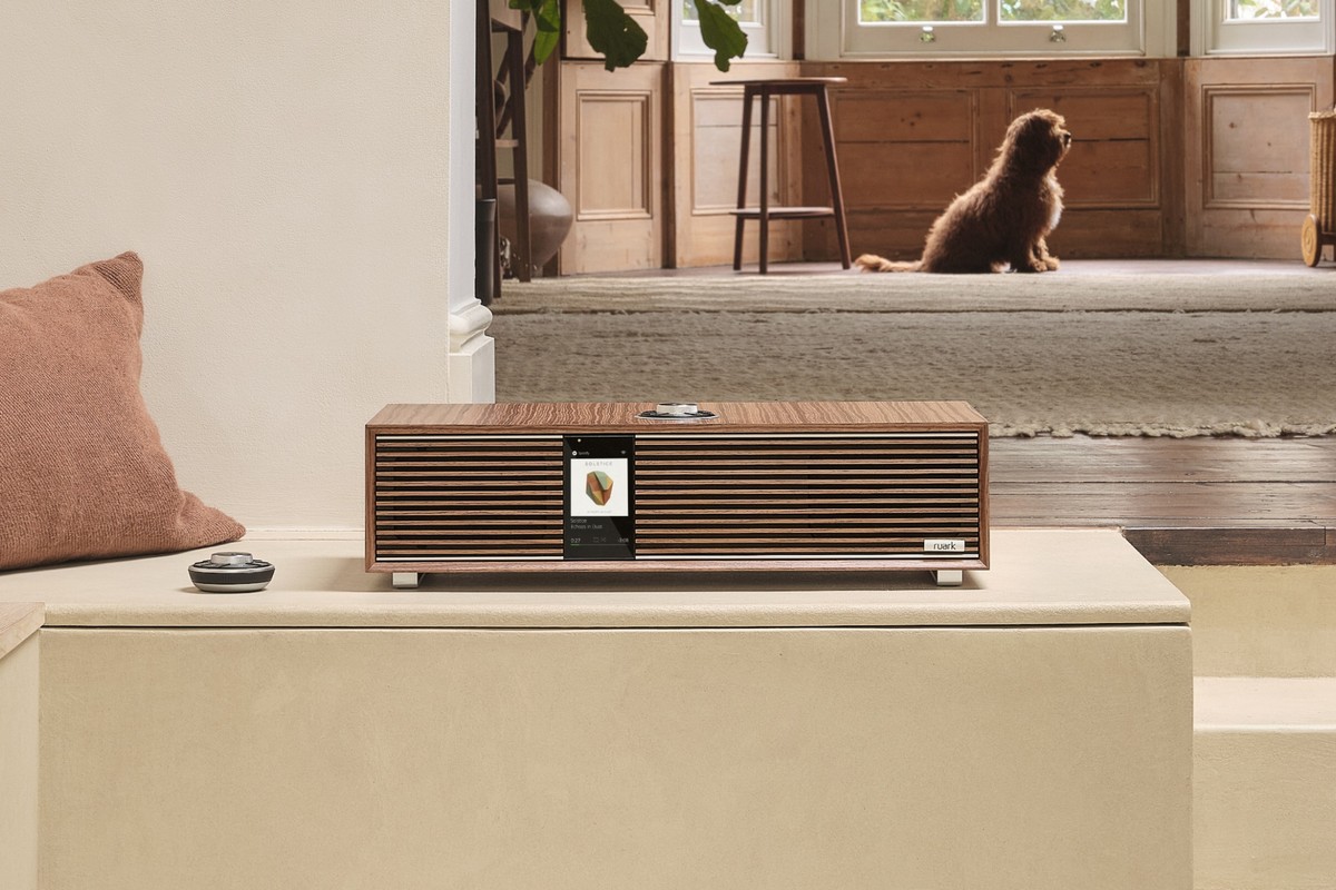 Walnut speaker on a cream bench, terracotta cushion and the home interior behind