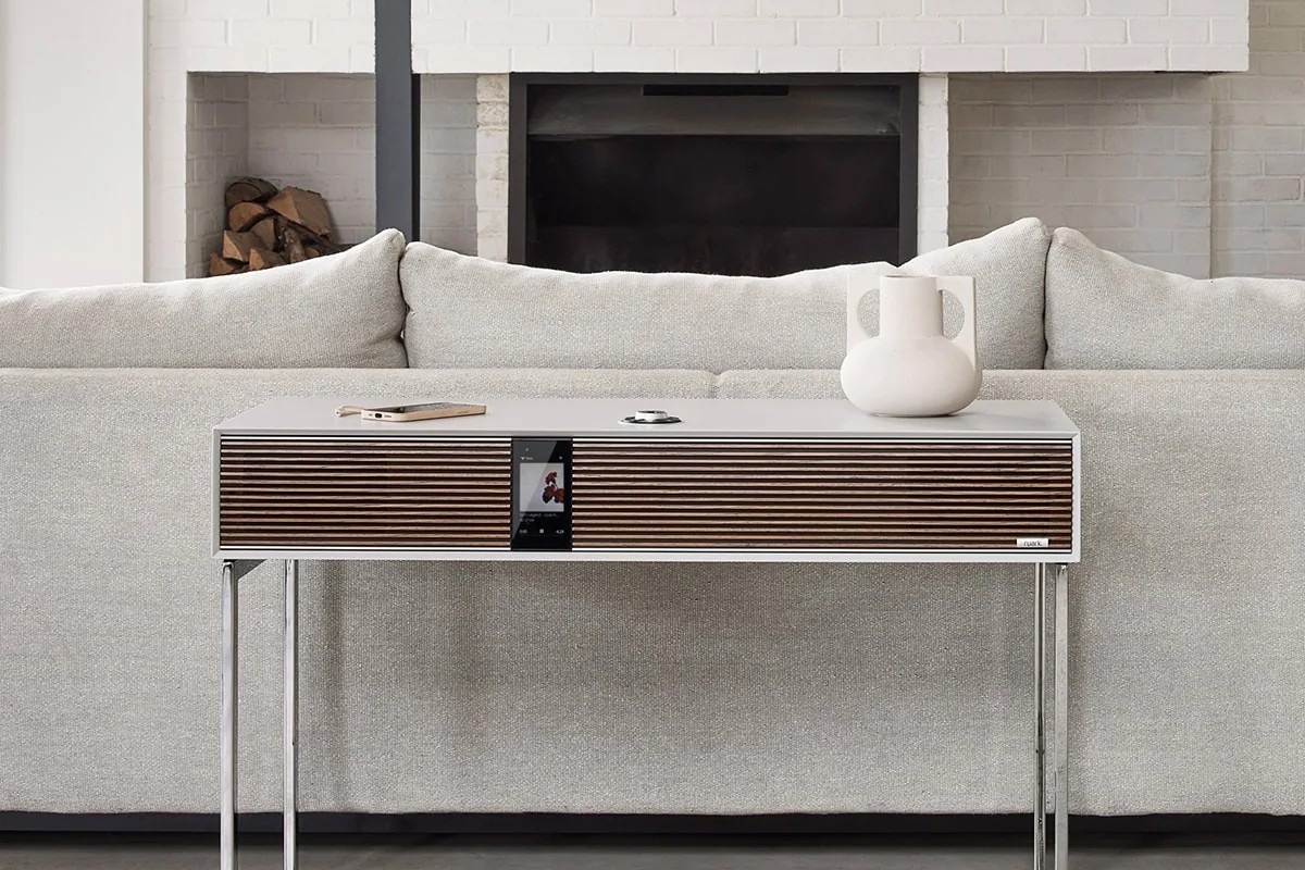 Ruark R810 Soft Grey radiogram in front of a light grey sofa and a white brick fireplace