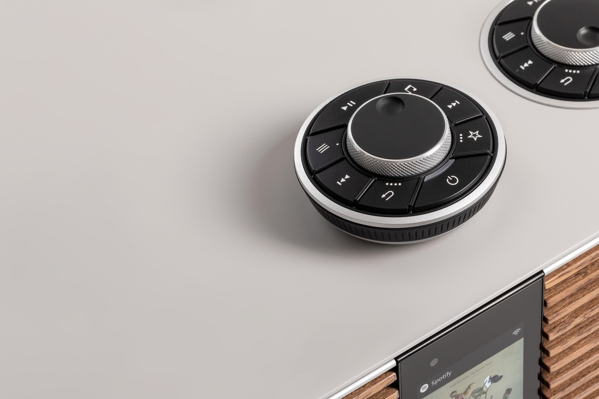Close-up of the grey lacquered top: rechargeable remote control resting on it, RotoDial and the unit's colour screen