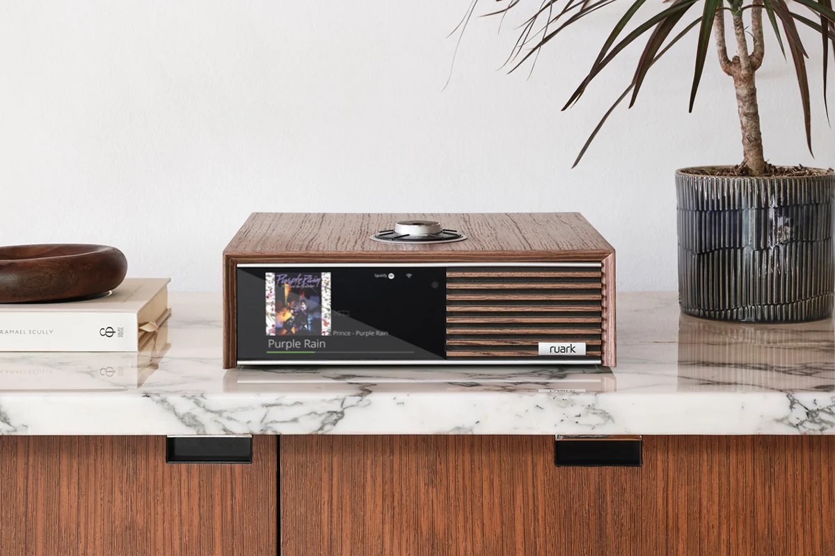 Console en noyer sur un plateau de marbre, écran allumé, plante et livres