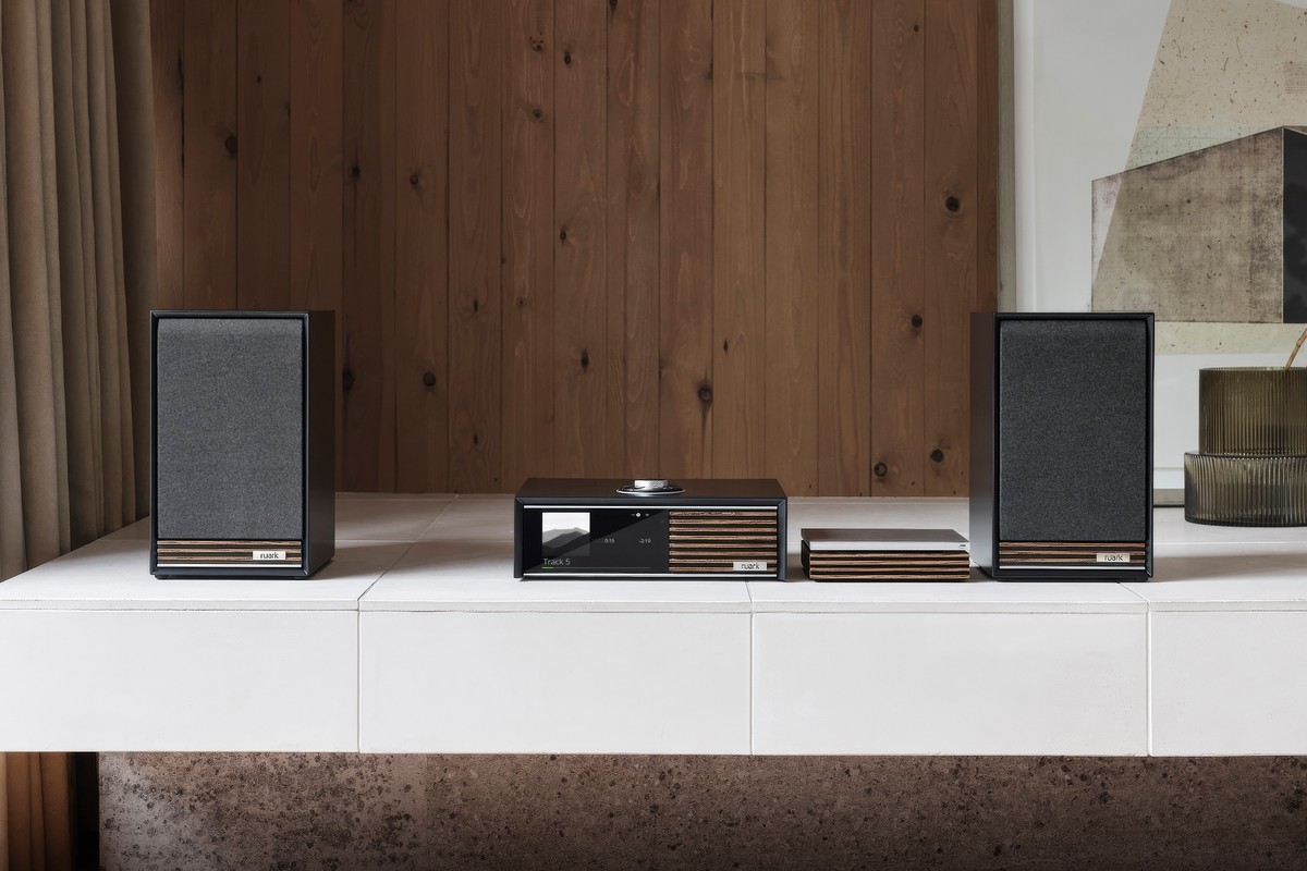 Console laquée charbon et lecteur CD sur un meuble blanc, entre deux enceintes noires