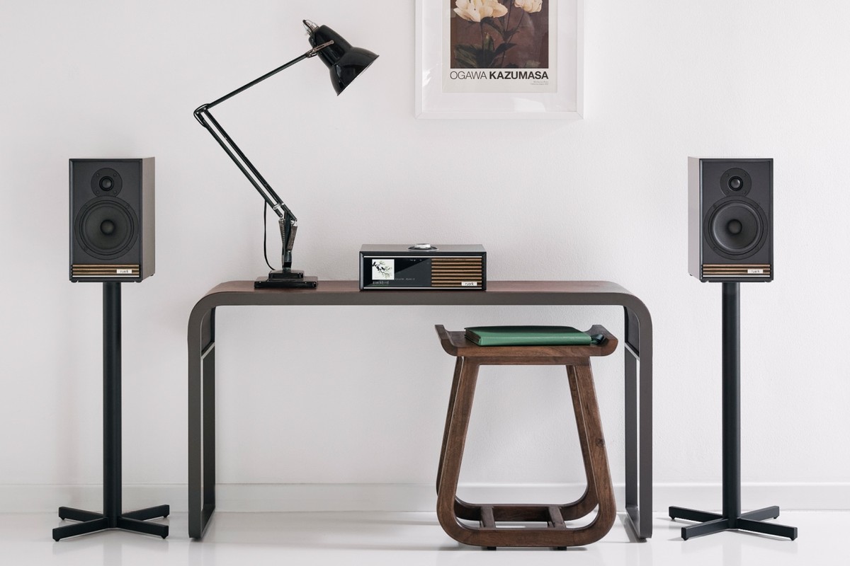 Console laquée charbon sur une console de bureau entre deux enceintes sur pieds
