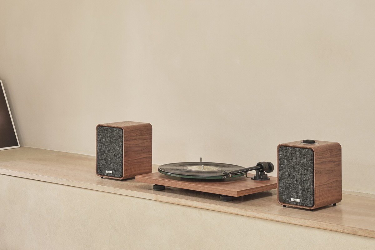Coppia di diffusori attivi Ruark Audio MR1 Mk3 su una mensola in pietra chiara, con un giradischi tra i due