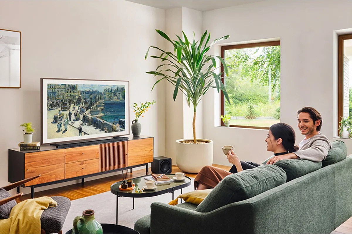 Couple dans un salon lumineux devant le téléviseur posé sur un meuble