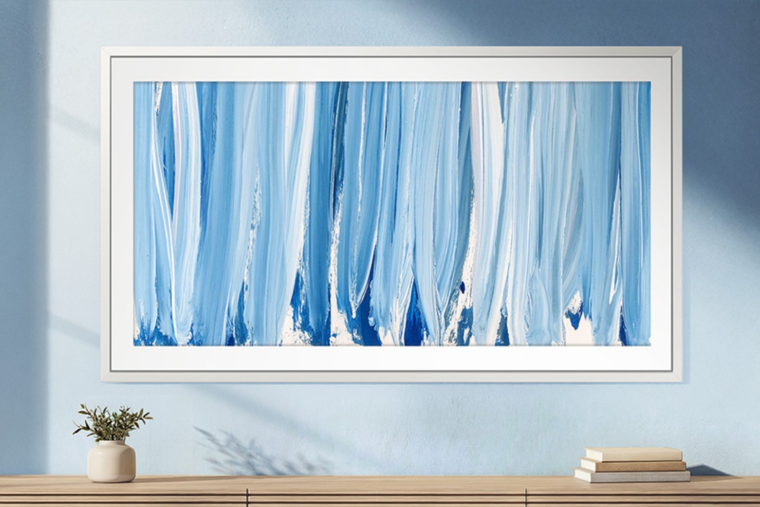 Blue abstract canvas in a white frame on a sunlit wall