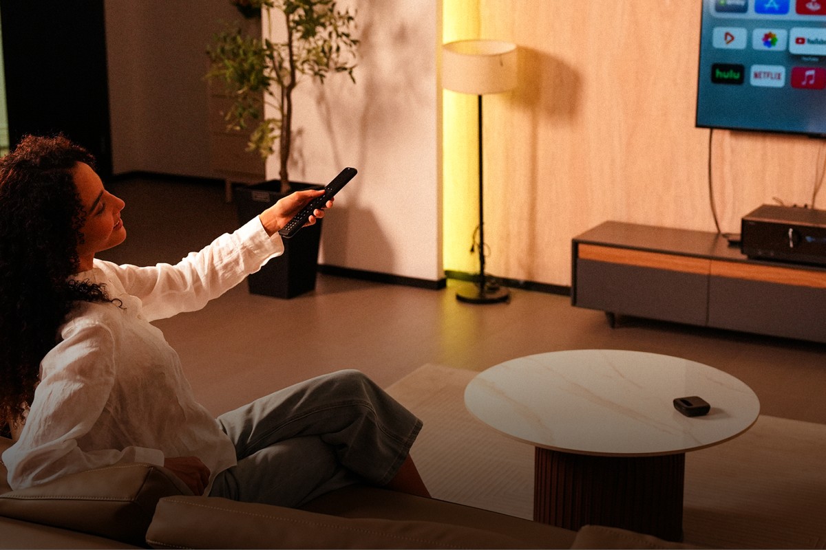 Woman pointing her remote at a television in a living room