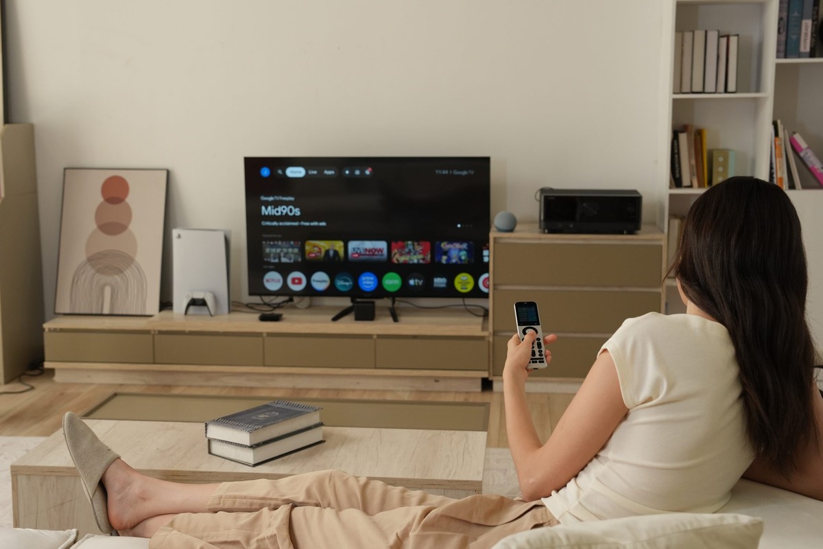 Donna che avvia un'attività dal telecomando SofaBaton X2, davanti a un televisore