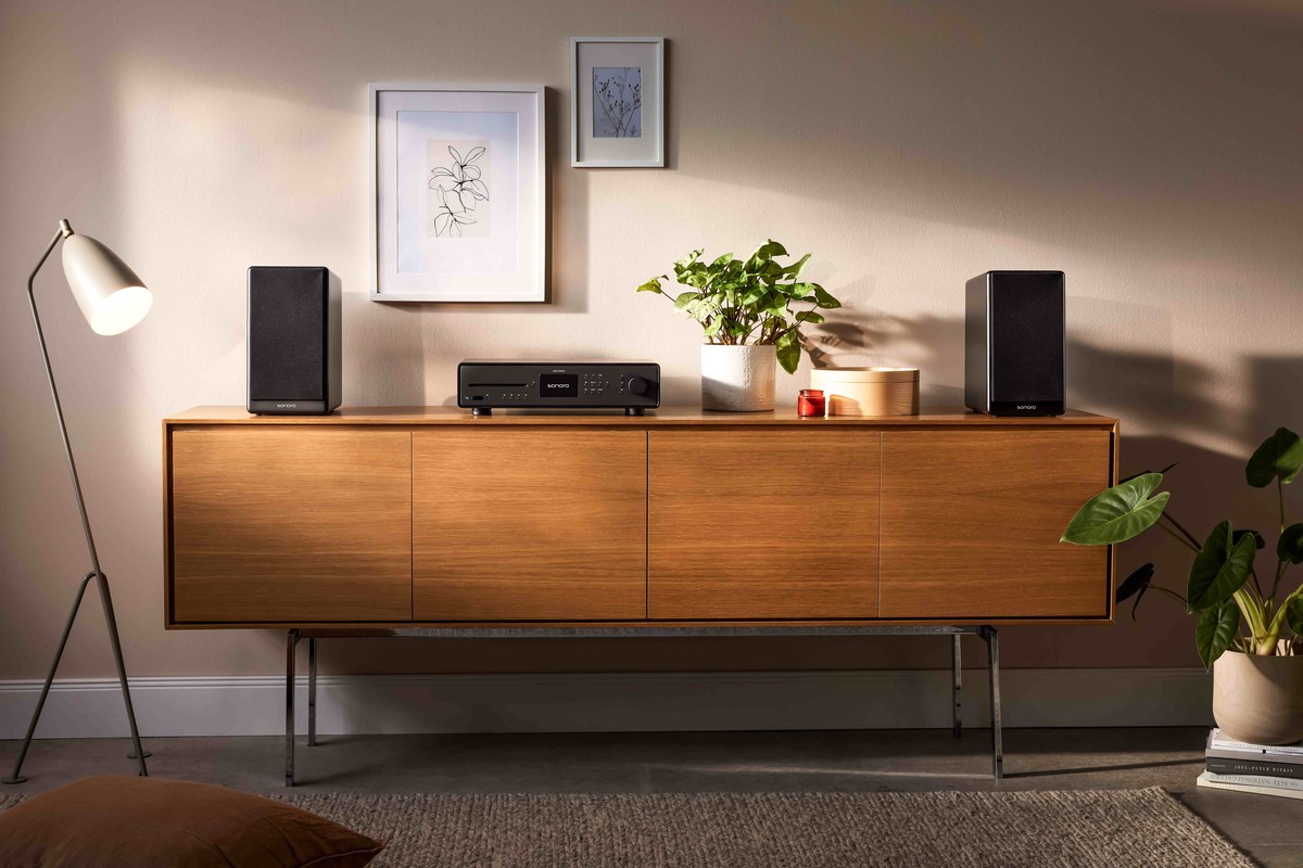 Schwarzer Receiver auf einem Nussbaum-Sideboard zwischen zwei Kompaktlautsprechern