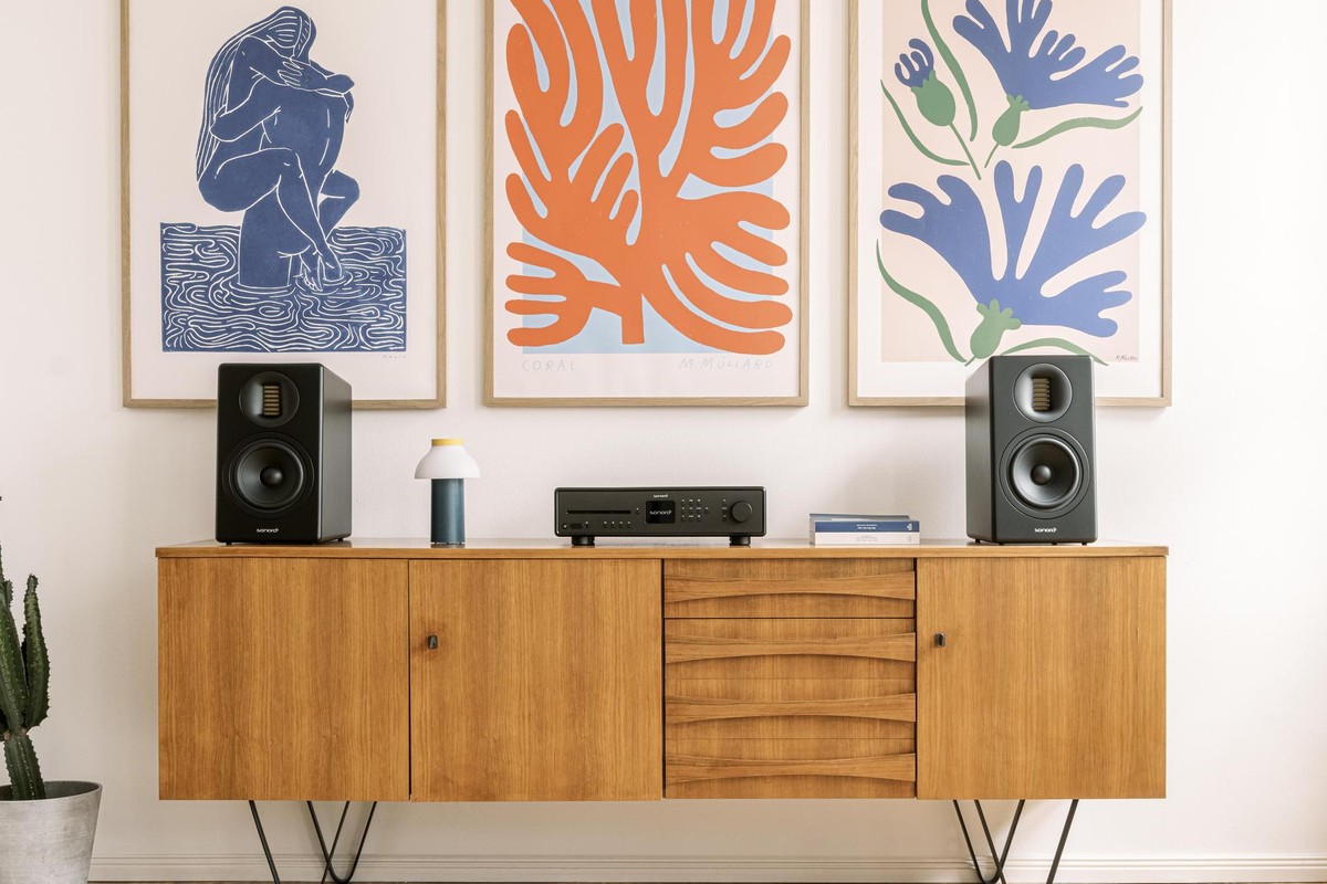 Zwei schwarze Lautsprecher auf einem Teak-Sideboard, Receiver in der Mitte