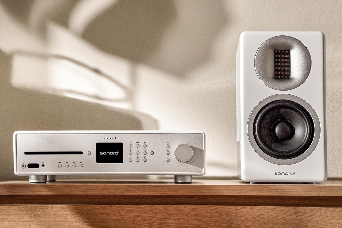White speaker next to a silver receiver on a wooden top