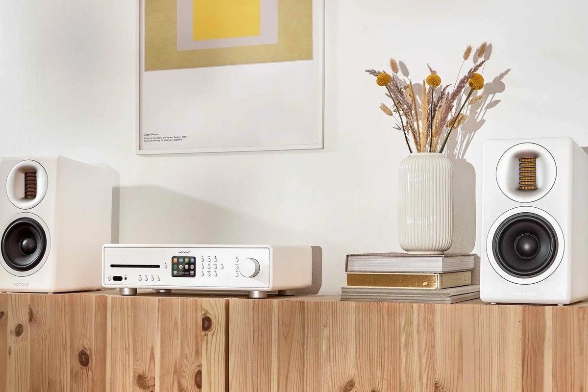 White Sonoro Orchestra Slim on each side of a receiver on a sideboard