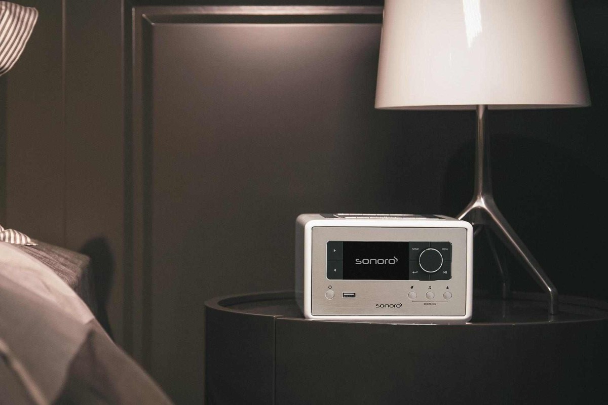 White radio on a black nightstand in the soft light of a bedroom