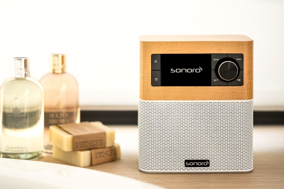 Sonoro Stream in maple decor on a bathroom shelf among soaps and bottles
