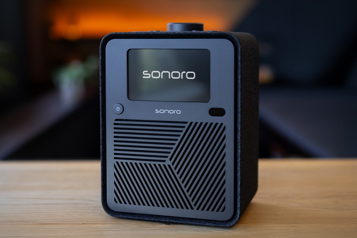 Sonoro ATRON noir posé sur une table en bois, lumière orangée tamisée en arrière-plan