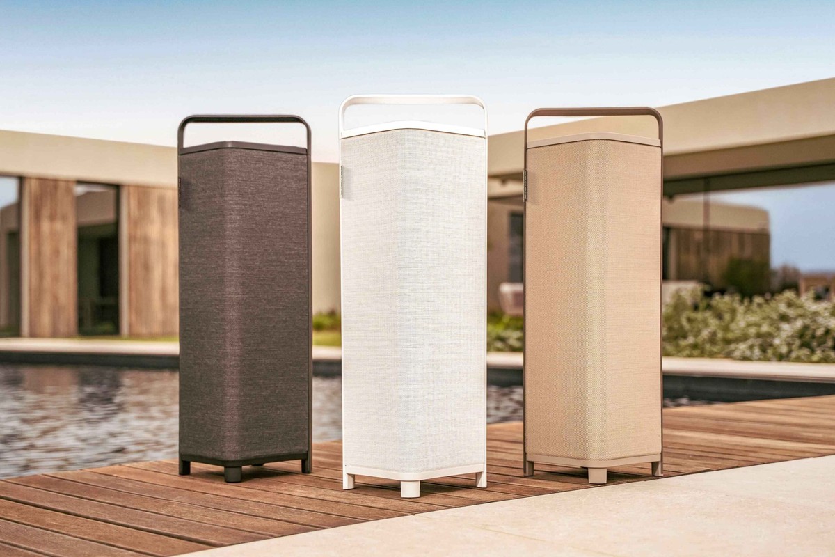 Tre diffusori nero, bianco e beige allineati su una passerella di legno accanto a una piscina