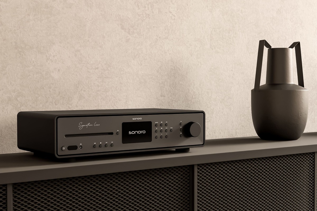 Ampli-tuner noir posé sur un buffet gris, vase sombre contre un mur enduit