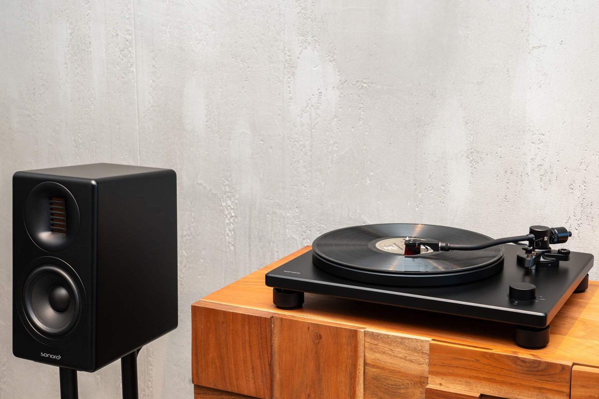 Platine vinyle noire sur un cube en bois, à côté d'une enceinte compacte