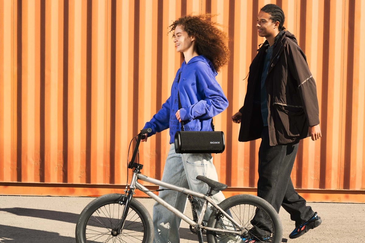 Deux jeunes avec un BMX, enceinte noire portée en bandoulière