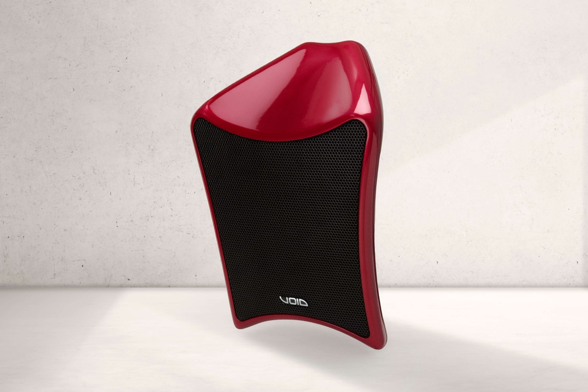 Enceinte Void Acoustics Air 8.1 rouge devant un mur en béton clair