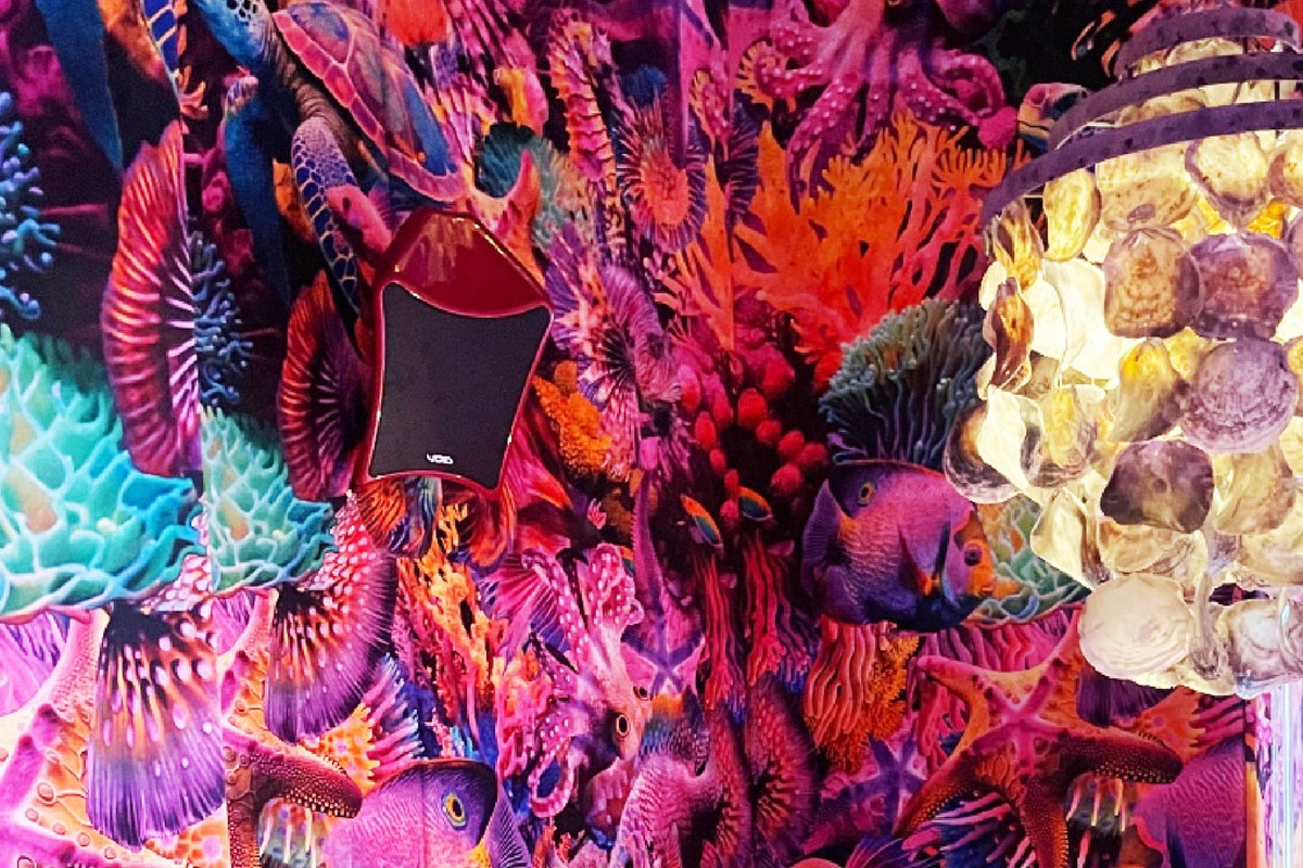 Enceinte rouge à grille noire fixée sur un décor mural coloré dans un restaurant de Barcelone