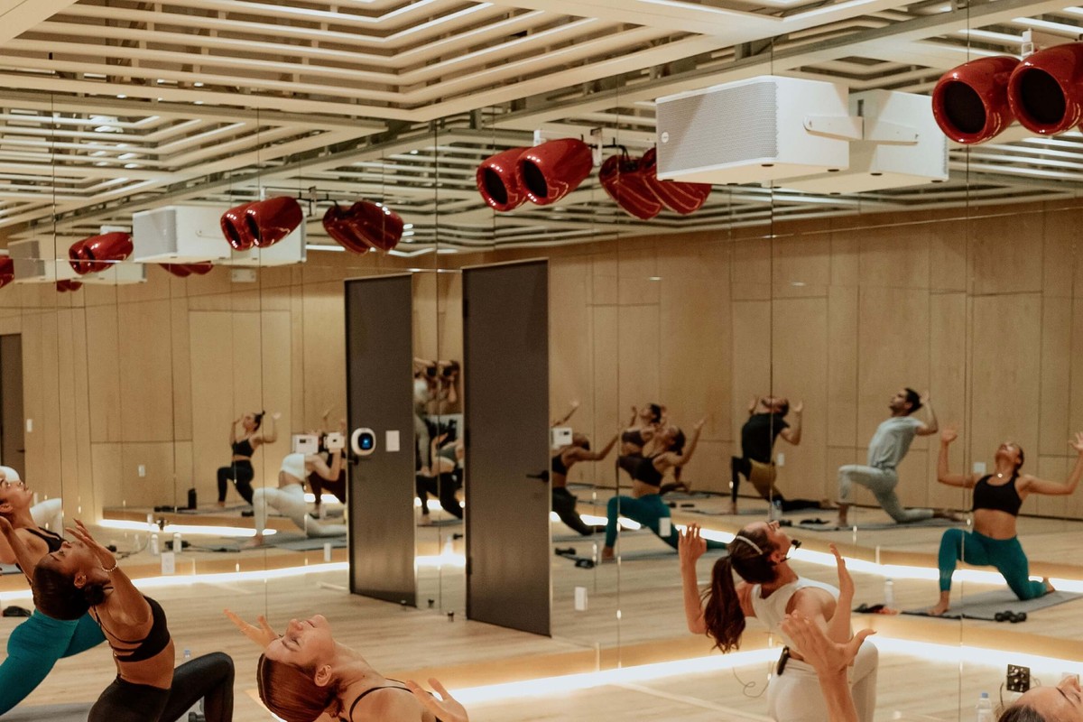 Enceintes rouges suspendues au plafond d'une salle de fitness aux parois miroir