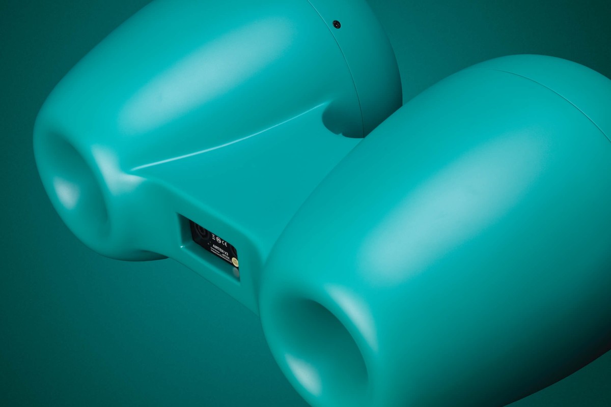 Vue arrière d'une enceinte turquoise avec ses deux évents et la plaque de connexion