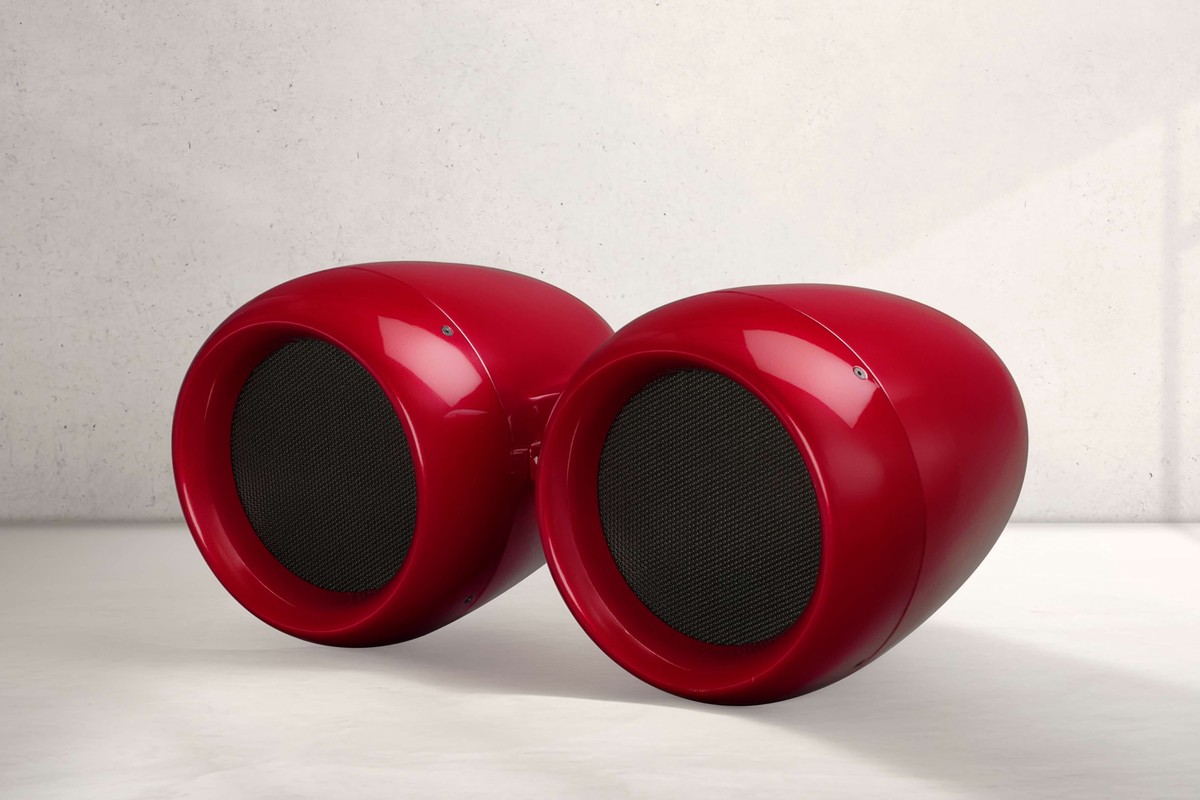 Enceinte Void Acoustics Airten V3 rouge devant un mur en béton clair