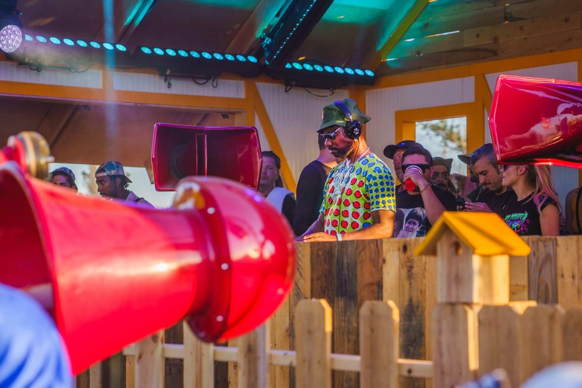 Cabine de DJ sur une scène de festival avec des enceintes rouges à trompe en retour