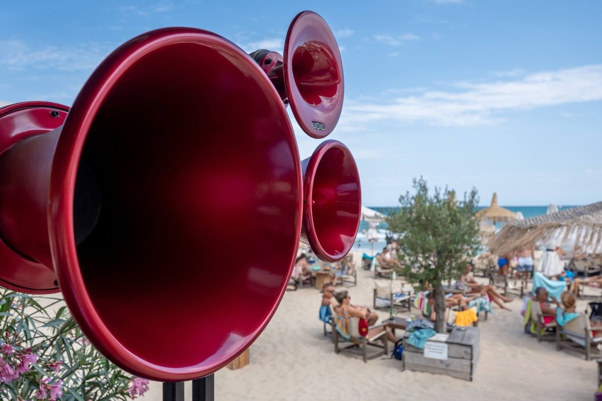 Cornets rouges d'une enceinte face à une terrasse de plage animée
