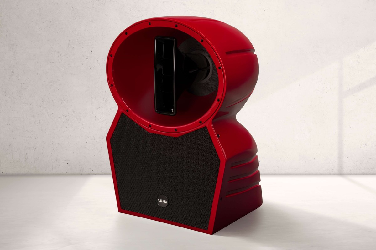 Enceinte Void Acoustics Air Stream rouge à grille noire devant un mur en béton clair