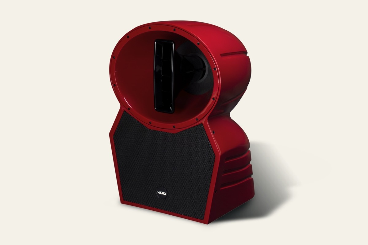 Boîtier rouge à grille noire et cornet du médium-aigu, vu de trois quarts sur fond crème