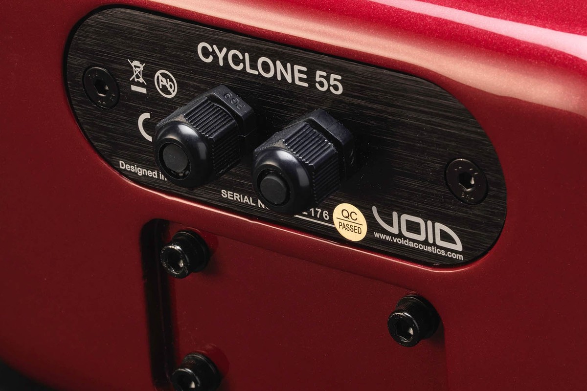 Face arrière d'une enceinte rouge avec ses deux presse-étoupes et sa plaque signalétique